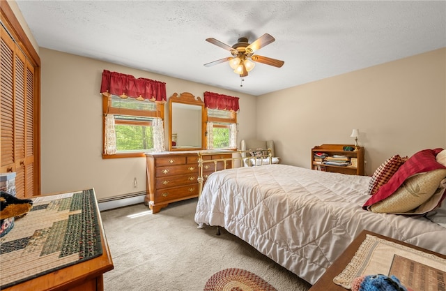 bedroom with baseboard heating, carpet, a textured ceiling, ceiling fan, and a closet