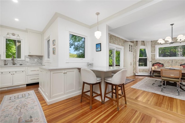 3 Hidden St, Providence, RI 02906 - kitchen featuring a sink, light wood-style floors, white cabinetry, a peninsula, and light countertops
