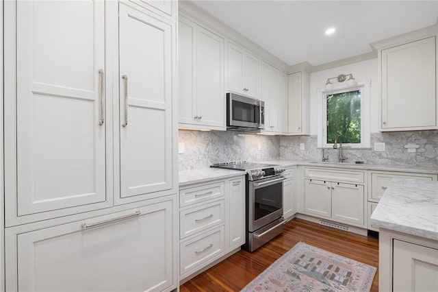 3 Hidden St, Providence, RI 02906 - kitchen featuring appliances with stainless steel finishes, a sink, backsplash, white cabinets, and dark wood-type flooring