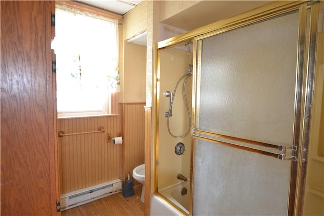 full bathroom featuring a baseboard heating unit, toilet, a wainscoted wall, bath / shower combo with glass door, and wood finished floors