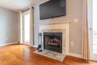unfurnished living room with wood finished floors, a fireplace with flush hearth, and baseboards