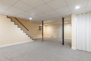 finished below grade area featuring baseboards, stairway, recessed lighting, carpet flooring, and a paneled ceiling