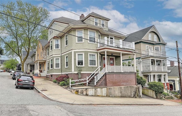 view of front facade featuring a balcony, a chimney, and covered porch