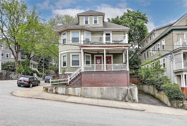 american foursquare style home featuring covered porch, a balcony, and roof with shingles