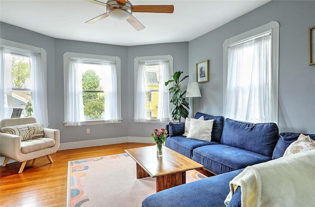 living room with plenty of natural light, a ceiling fan, light wood-style floors, and baseboards