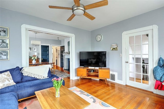living room featuring wood finished floors, ceiling fan, and a fireplace with flush hearth
