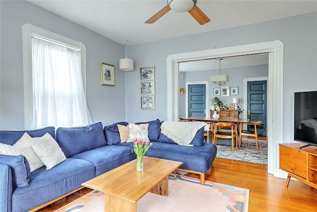 living room featuring light wood finished floors and a ceiling fan