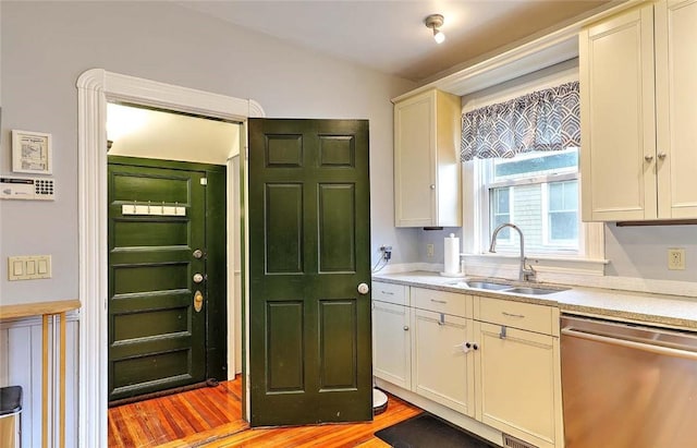 kitchen featuring dishwasher, a sink, light wood finished floors, and white cabinetry