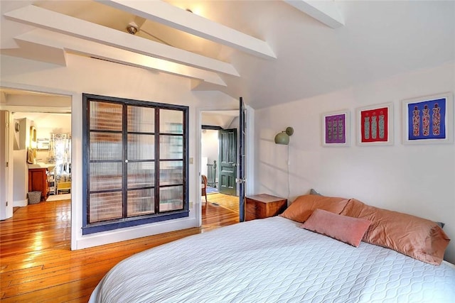 bedroom with beamed ceiling and light wood finished floors