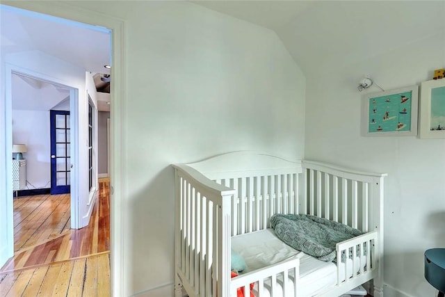 bedroom featuring lofted ceiling, wood-type flooring, and baseboards