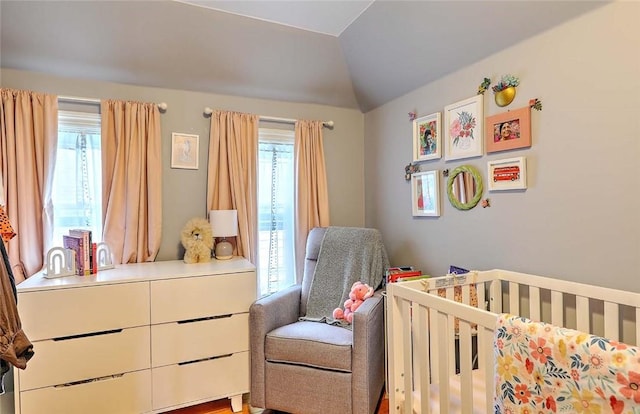 bedroom featuring multiple windows, a crib, and lofted ceiling