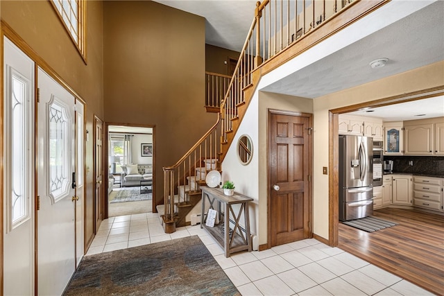 101 Nancy Ln, Burrillville, RI 02830 - entryway featuring light tile patterned flooring, stairs, a towering ceiling, and baseboards