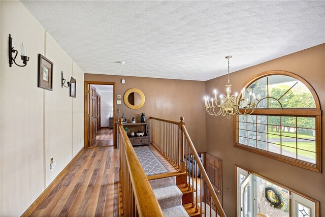 101 Nancy Ln, Burrillville, RI 02830 - corridor with a textured ceiling, wood finished floors, a chandelier, baseboards, and an upstairs landing