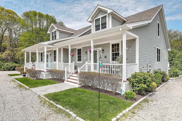 view of front of house with a porch, roof with shingles, and a front lawn