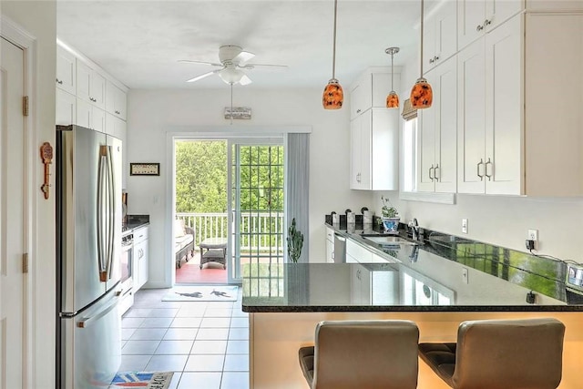 kitchen with appliances with stainless steel finishes, a ceiling fan, a sink, white cabinets, and tile patterned flooring