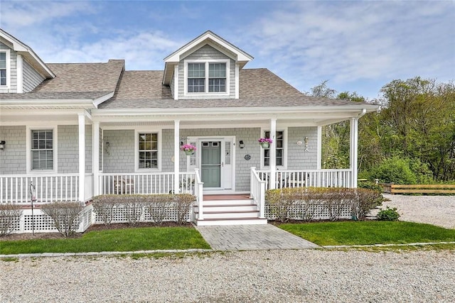 view of front facade featuring covered porch and a shingled roof