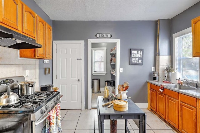 10 Westcott Ave Unit 1, Boston, MA 02124 - kitchen featuring gas range, under cabinet range hood, a sink, light tile patterned flooring, and backsplash