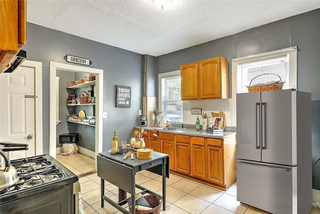 10 Westcott Ave Unit 1, Boston, MA 02124 - kitchen with freestanding refrigerator, gas stove, a sink, brown cabinets, and a textured ceiling