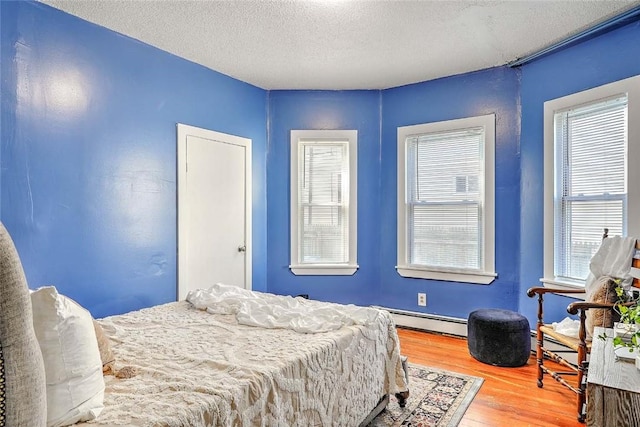 10 Westcott Ave Unit 1, Boston, MA 02124 - bedroom with a baseboard radiator, wood finished floors, multiple windows, a textured ceiling, and baseboards