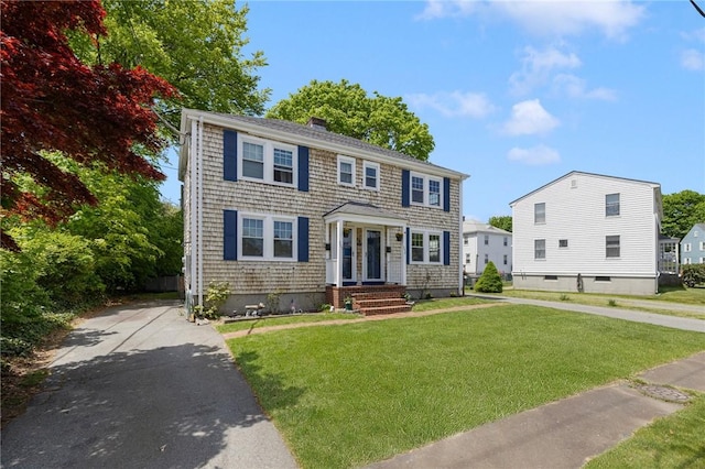 colonial home featuring a front lawn and a chimney