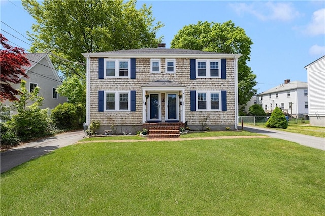 colonial house featuring a chimney, driveway, and entry steps