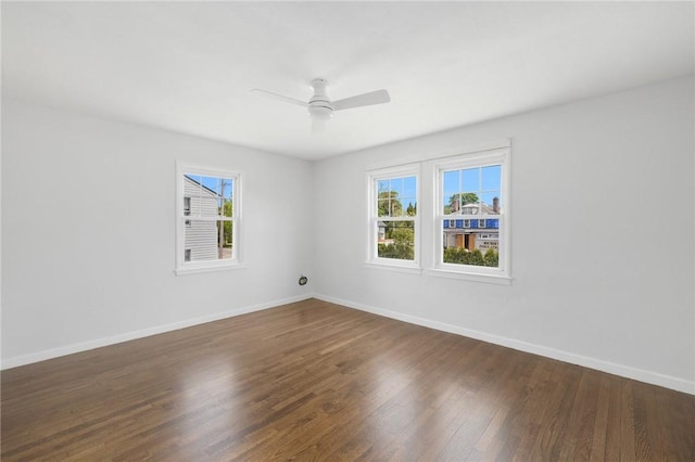 empty room featuring plenty of natural light, wood finished floors, a ceiling fan, and baseboards
