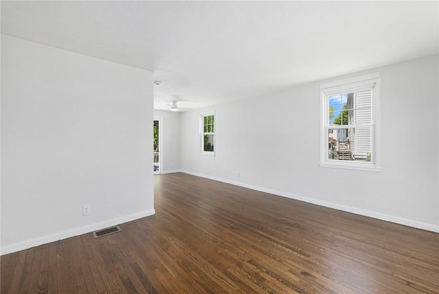 unfurnished room featuring healthy amount of natural light, baseboards, dark wood-style flooring, and a ceiling fan