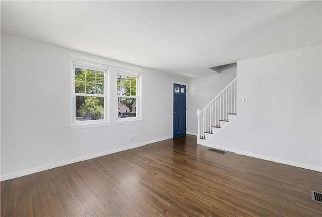 unfurnished living room with stairway, wood-type flooring, and baseboards