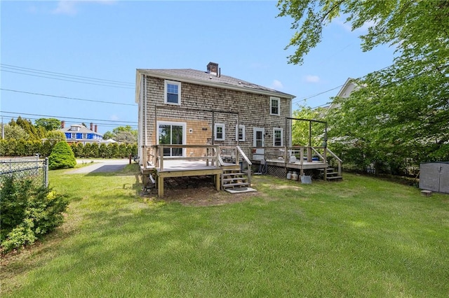 back of property with a wooden deck, a chimney, and roof with shingles