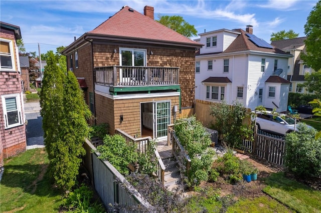 back of property with fence, a chimney, and roof with shingles