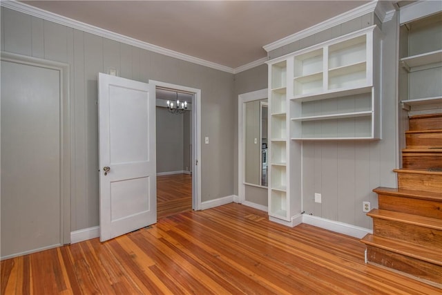 spare room with a chandelier, wood finished floors, baseboards, and ornamental molding