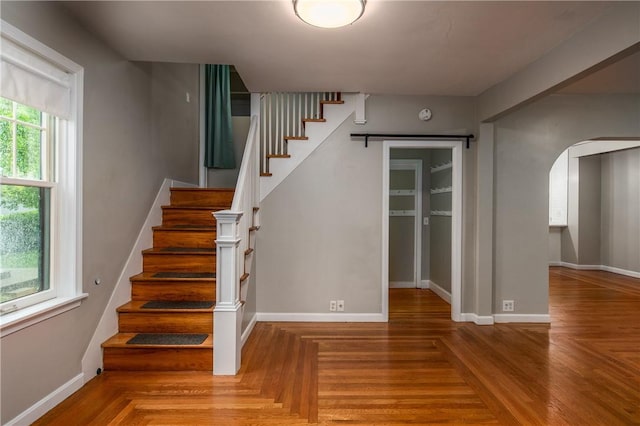 staircase with arched walkways and baseboards