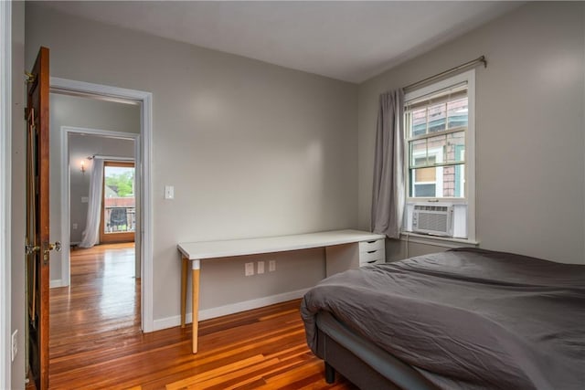 bedroom with wood finished floors, cooling unit, and baseboards