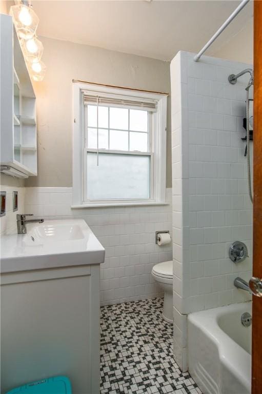 bathroom featuring tile walls, toilet, vanity, tile patterned floors, and a wainscoted wall