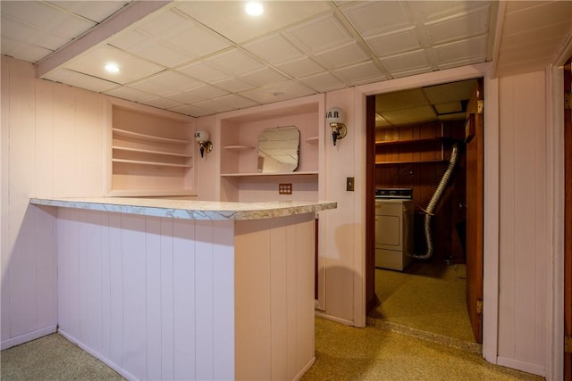 kitchen featuring washer / clothes dryer, light countertops, wood walls, and built in features