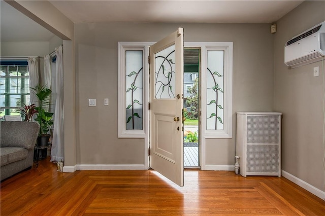 entryway with baseboards, an AC wall unit, light wood-style floors, and radiator heating unit