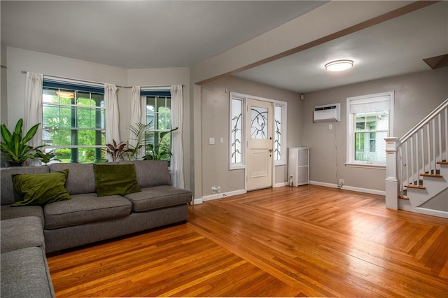 foyer entrance with an AC wall unit, stairs, baseboards, and light wood finished floors