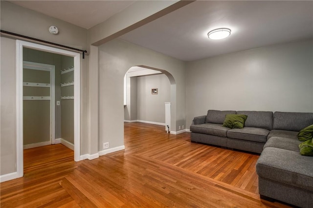 living area featuring arched walkways, wood finished floors, and baseboards