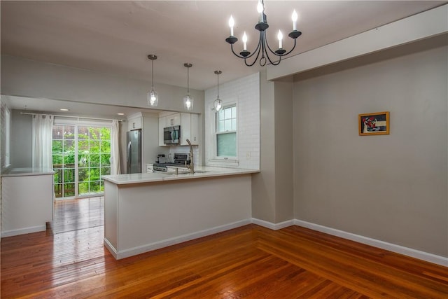 kitchen featuring appliances with stainless steel finishes, a chandelier, wood finished floors, and white cabinetry