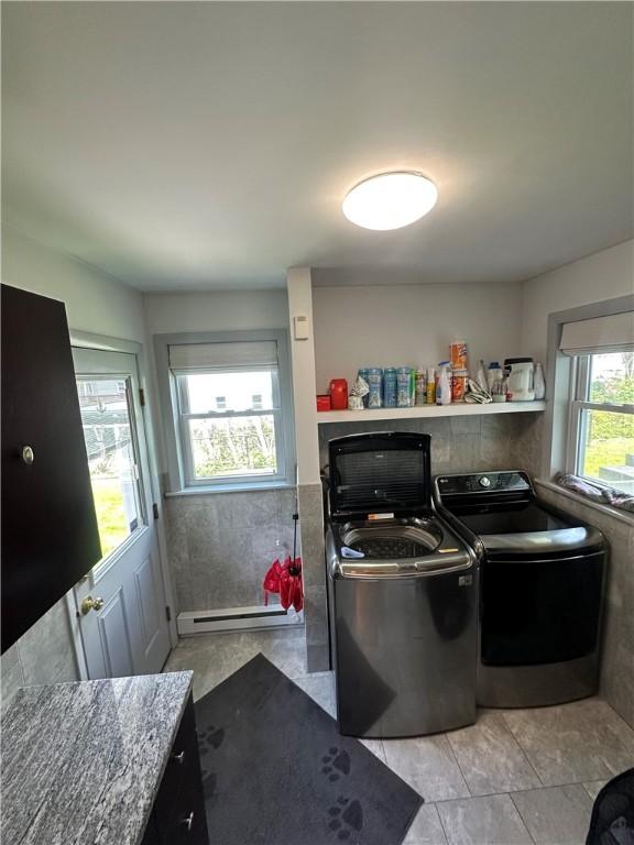 clothes washing area featuring a baseboard radiator, independent washer and dryer, and light tile patterned floors
