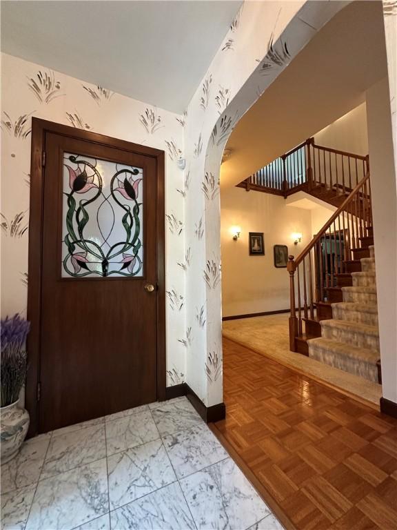 entryway with baseboards, arched walkways, and stairs