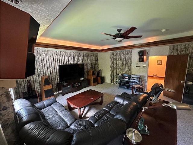 carpeted living area featuring ceiling fan and a raised ceiling