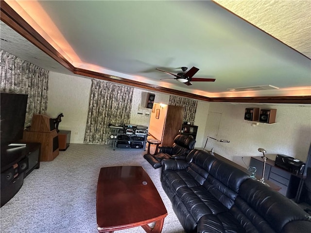 carpeted home theater room featuring a raised ceiling, a ceiling fan, and a textured wall