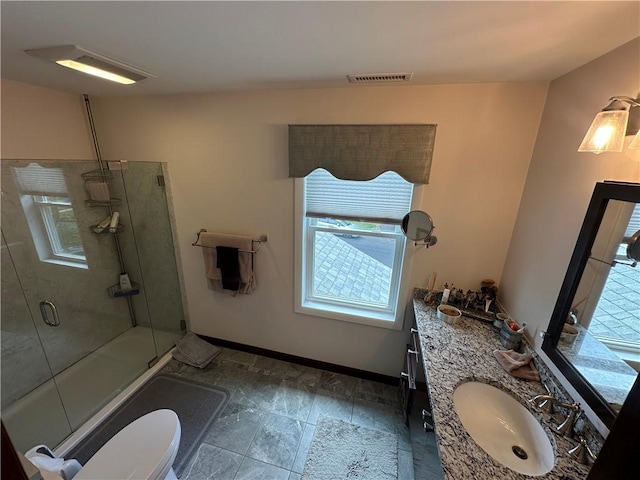 bathroom featuring an enclosed shower, double vanity, baseboards, toilet, and stone finish flooring
