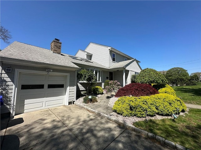 view of front of property with driveway, a chimney, a garage, and roof with shingles