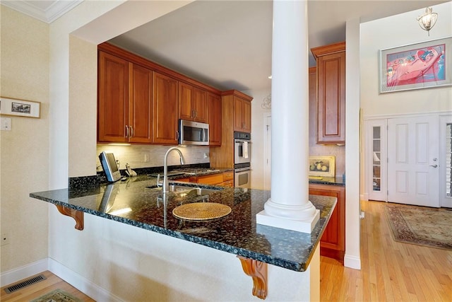 43 Waters Edge, Tiverton, RI 02878 - kitchen with decorative columns, stainless steel appliances, a sink, a breakfast bar, and ornamental molding