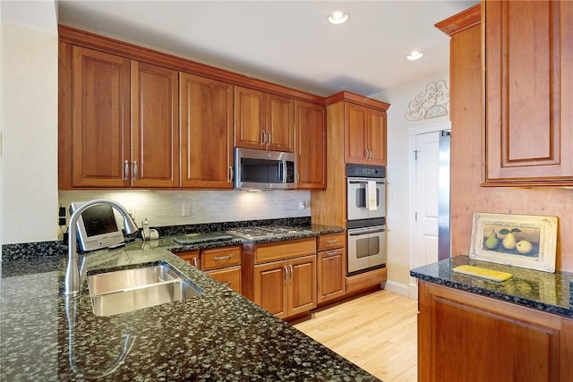 43 Waters Edge, Tiverton, RI 02878 - kitchen with stainless steel appliances, a sink, light wood-style floors, backsplash, and dark stone counters