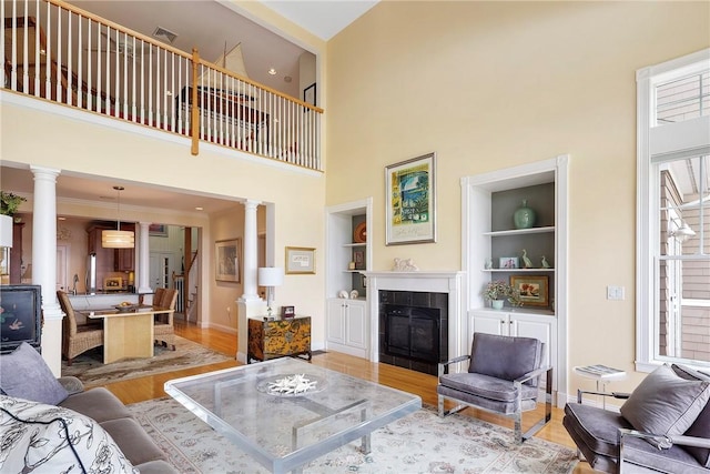 43 Waters Edge, Tiverton, RI 02878 - living area featuring ornate columns, a high ceiling, built in shelves, light wood-style flooring, and a fireplace