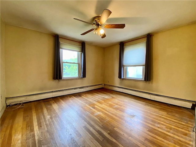 unfurnished room with wood finished floors, plenty of natural light, a ceiling fan, and baseboard heating