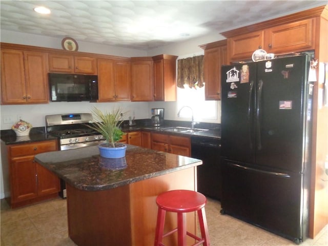 kitchen featuring black appliances, a sink, brown cabinets, a center island, and a breakfast bar
